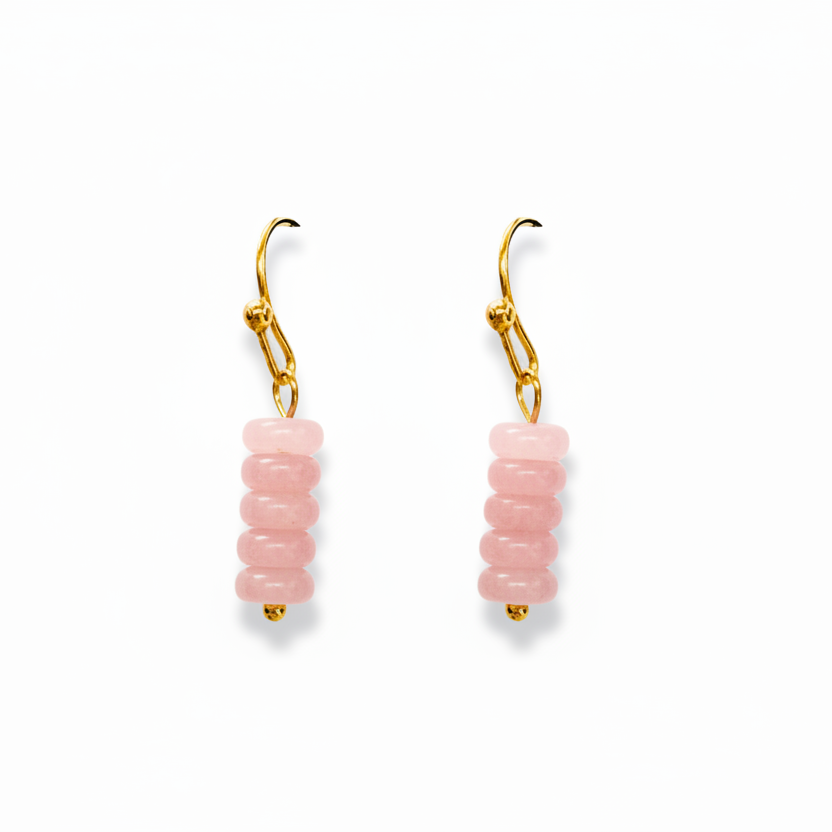 A pair of gold leverback drop earrings featuring a stacked column of round, light pink beads, shown against a plain white background.