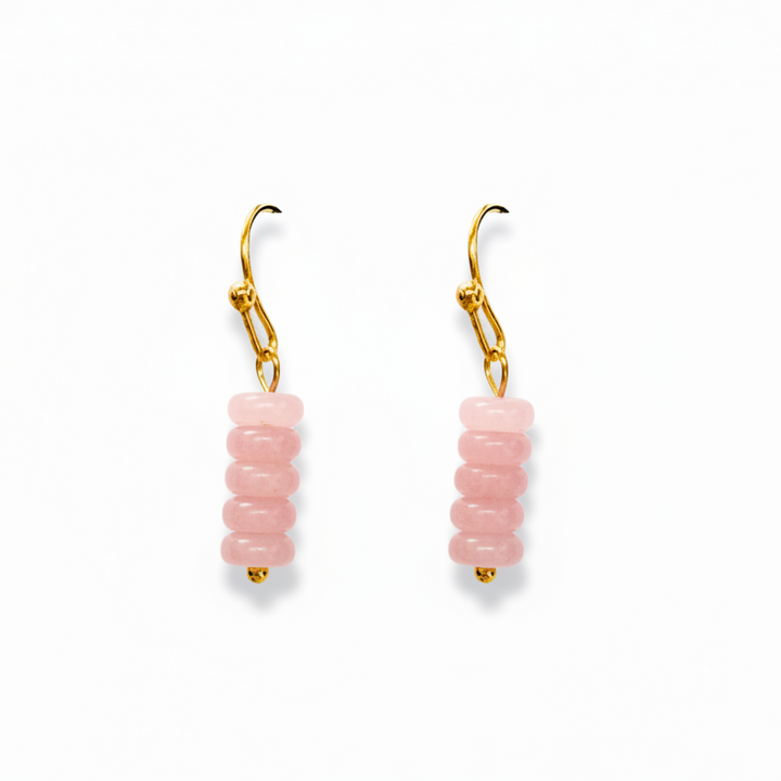 A pair of gold leverback drop earrings featuring a stacked column of round, light pink beads, shown against a plain white background.