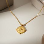 Gold necklace with a round pendant on a white background