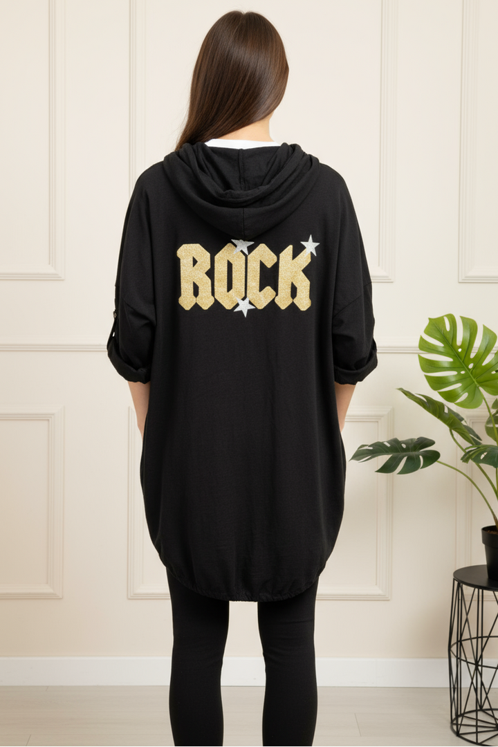 Person wearing a black hoodie with 'ROCK' text in gold, standing in a room with a plant.