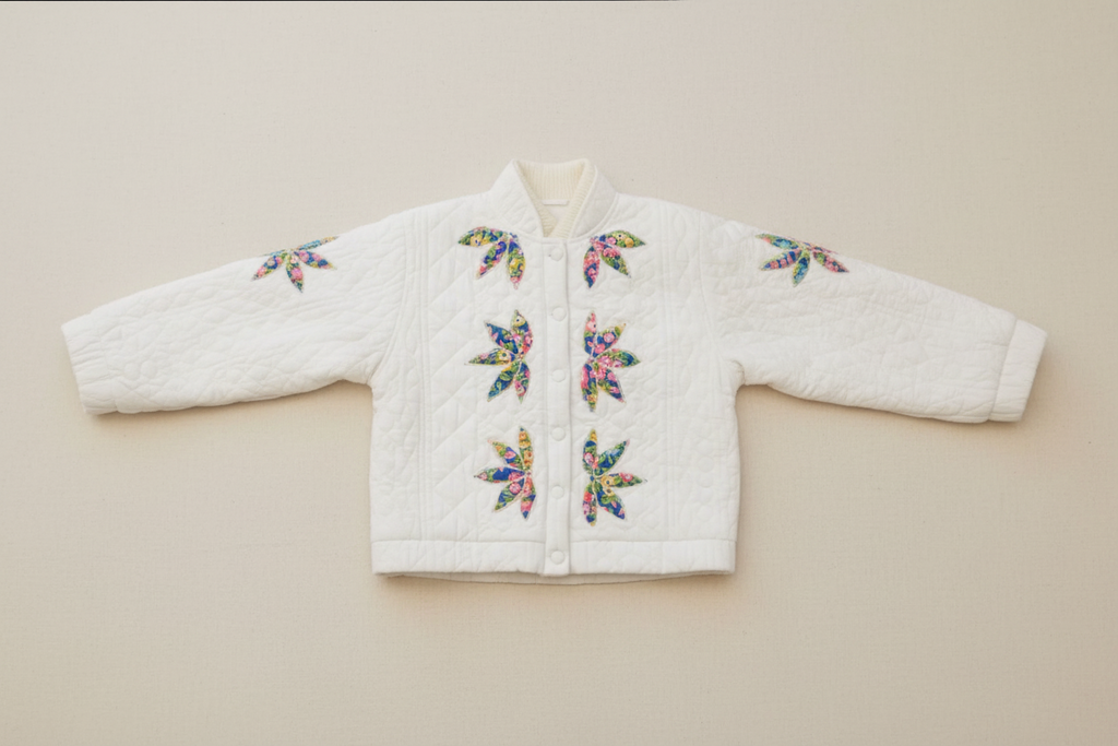 White quilted jacket with colorful floral butterfly patterns on a neutral background