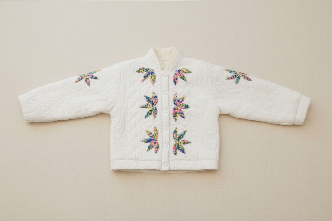 White quilted jacket with colorful floral butterfly patterns on a neutral background