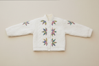 White quilted jacket with colorful floral butterfly patterns on a neutral background