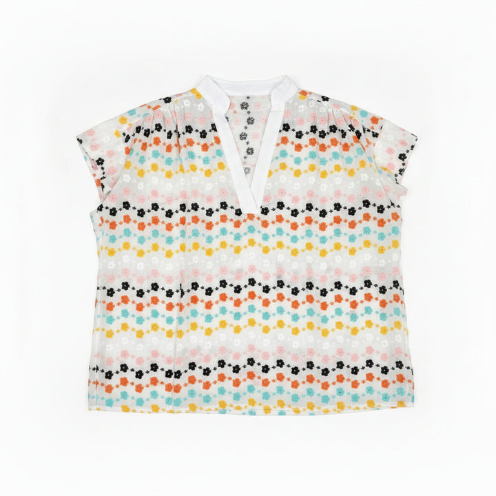 Floral blouse on a hanger against a wooden panel background