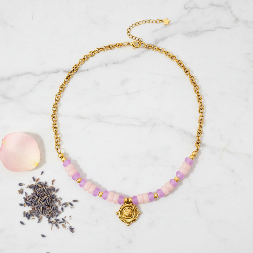 A gold chain necklace featuring a row of light pink faceted beads and a central gold pendant, displayed on a clean white background.