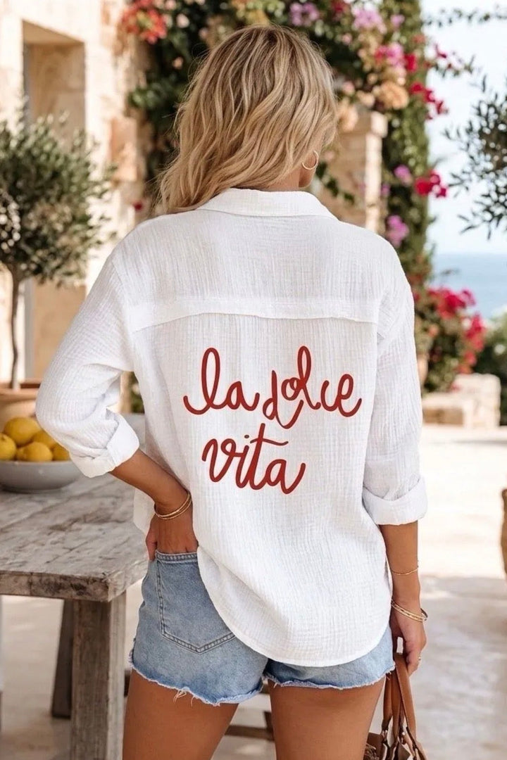 Person wearing a white shirt with 'la felice vita' text in an outdoor setting