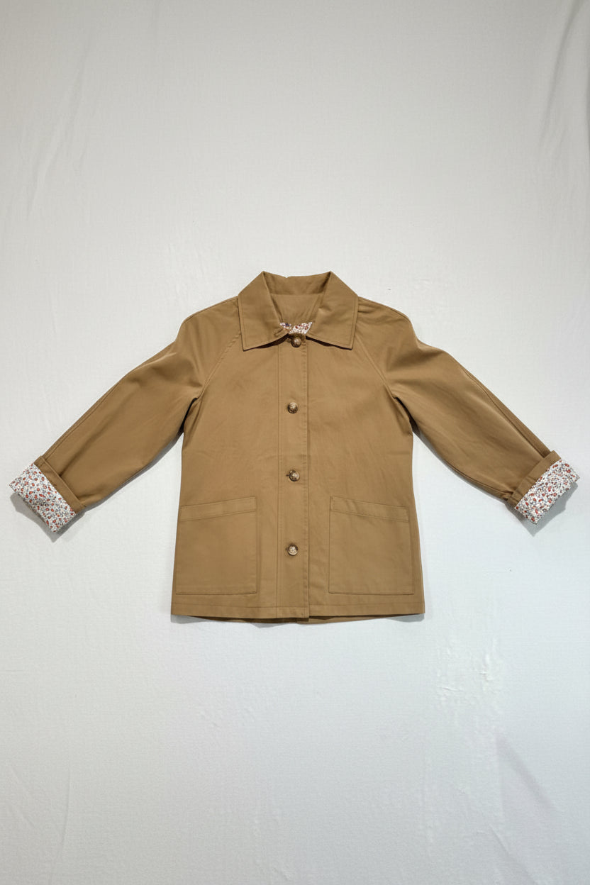 Brown jacket with floral cuffs and collar on a hanger against a white background