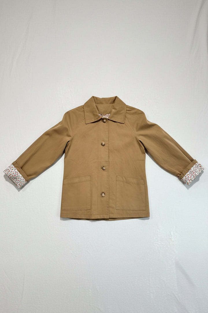 Brown jacket with floral cuffs and collar on a hanger against a white background