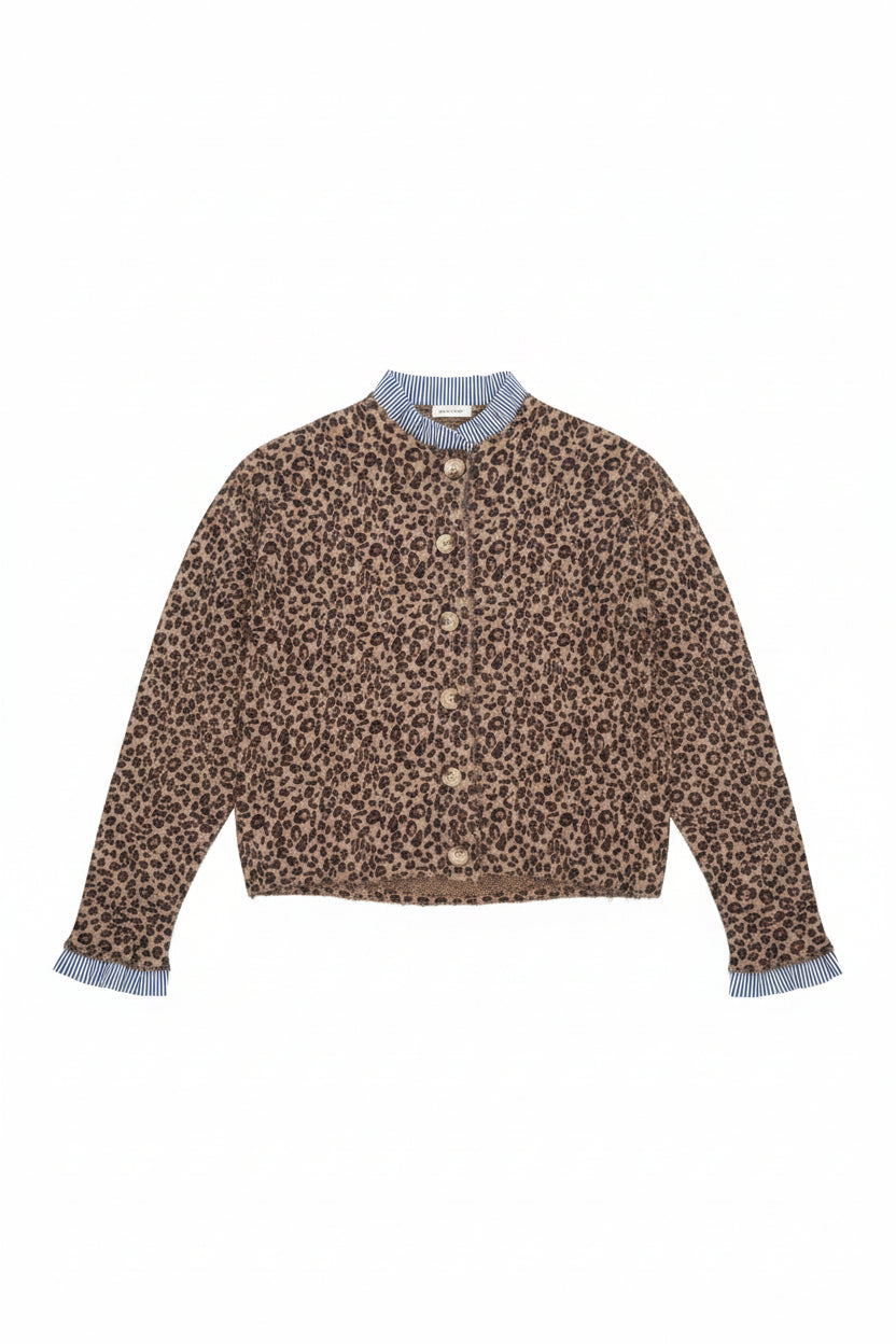 A leopard print cardigan sweater with a blue and white striped mock neck collar and striped cuffs, hanging on a white hanger on a store table.
