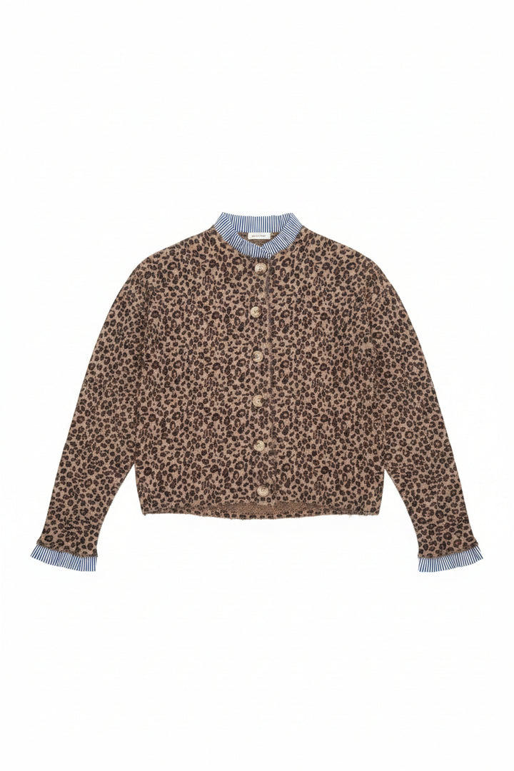 A leopard print cardigan sweater with a blue and white striped mock neck collar and striped cuffs, hanging on a white hanger on a store table.