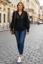 Person wearing a dark blue embroidered jacket and jeans indoors.