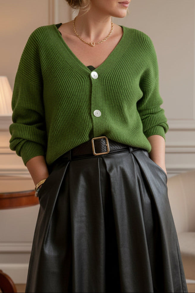 A person taking a mirror selfie wearing a bright green ribbed knit cardigan with white buttons, paired with a black skirt and a brown belt with a square buckle.