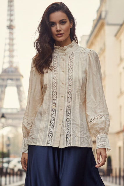 Beige embroidered blouse on a wooden hanger against a plain background