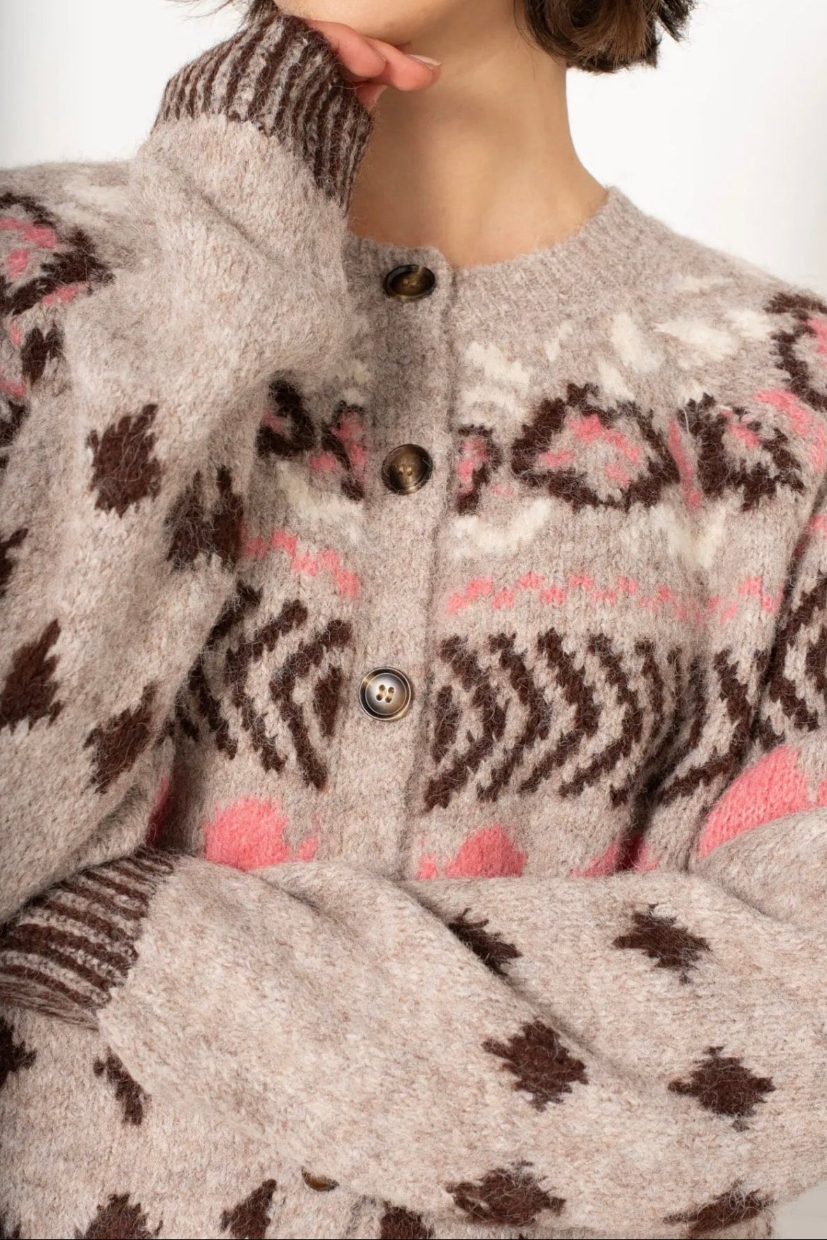 Close-up of a person wearing a patterned cardigan with a neutral background
