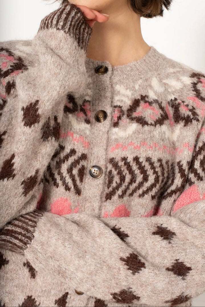 Close-up of a person wearing a patterned cardigan with a neutral background