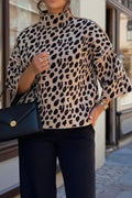 Person wearing a leopard print sweater and black pants, holding a black handbag.