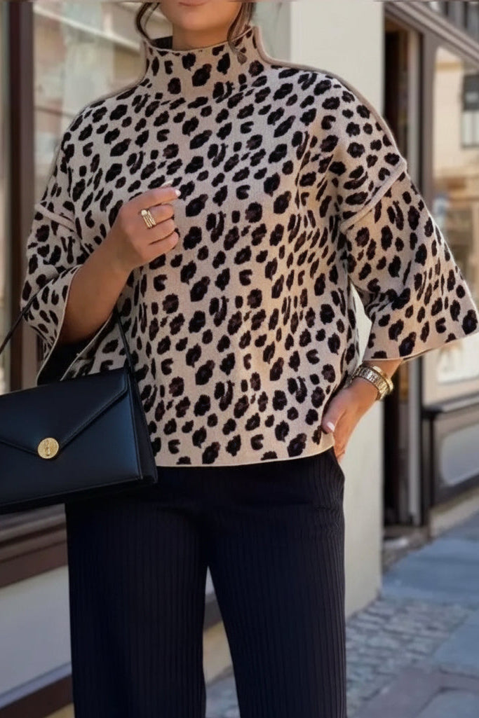Person wearing a leopard print sweater and black pants, holding a black handbag.