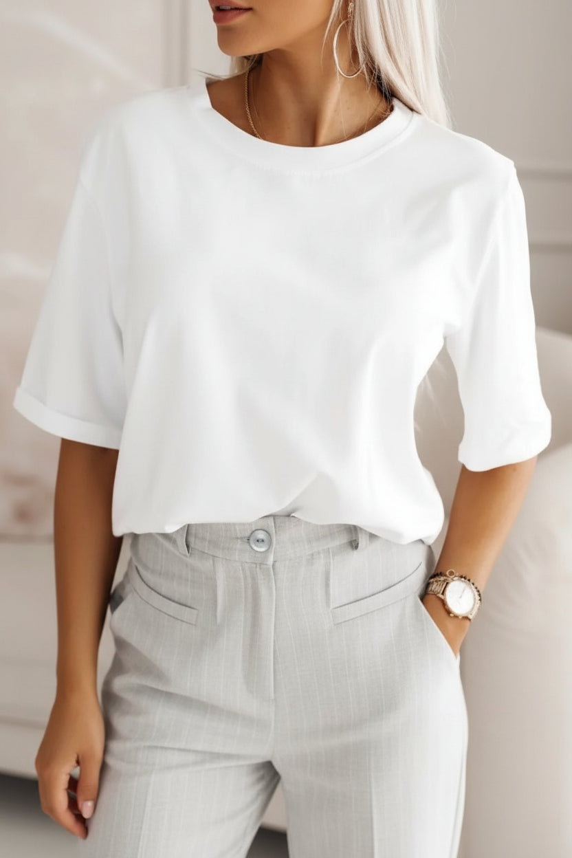 Person wearing a white t-shirt and gray pants with a neutral background