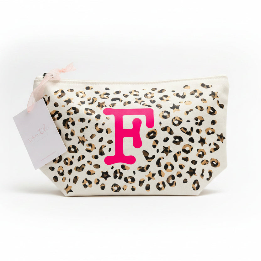 Leopard print pouch with pink letter 'F' on a textured surface