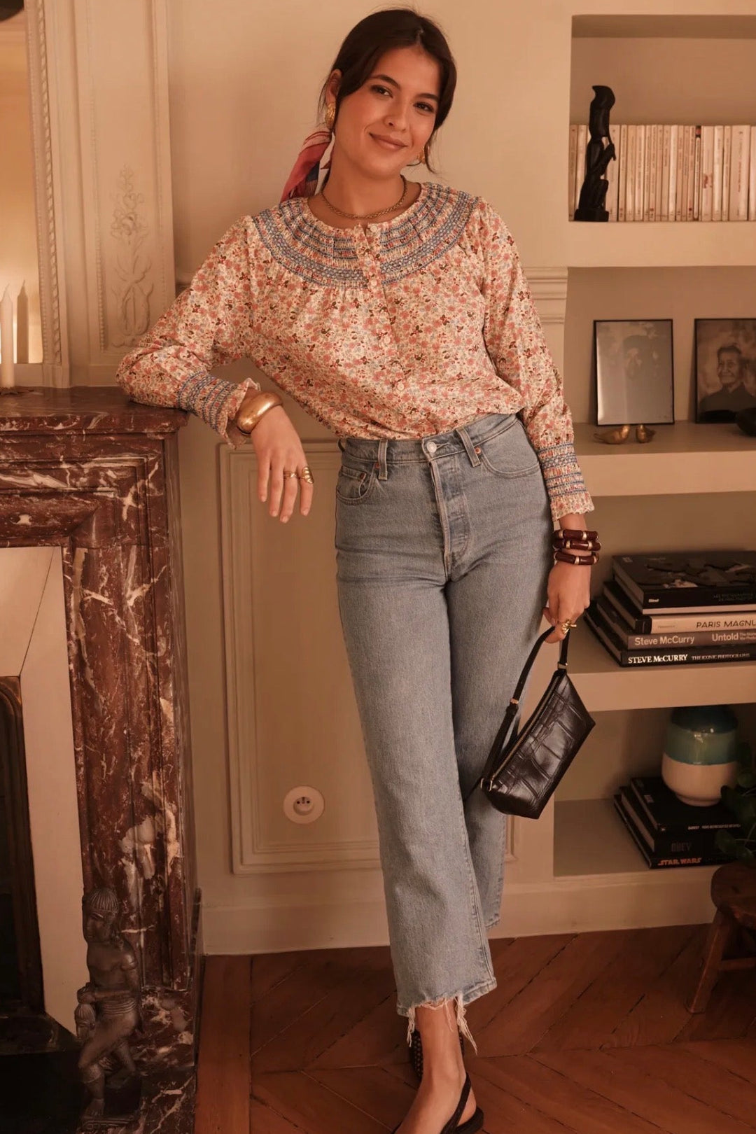 Woman posing in a room with a fireplace and shelves.