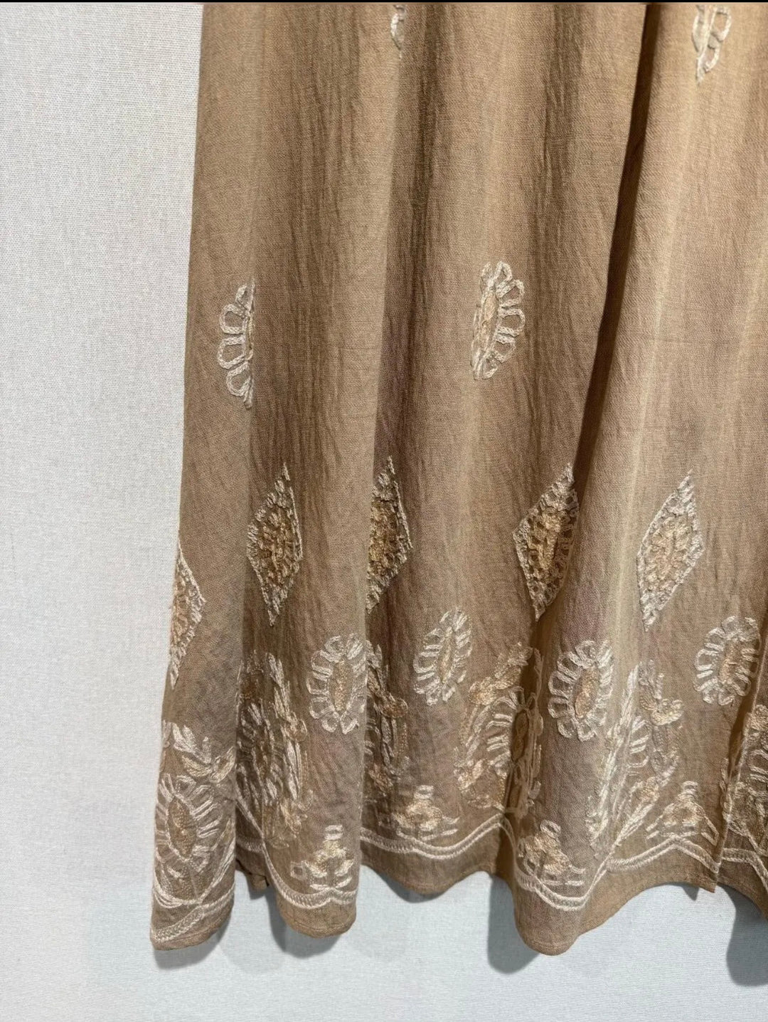 Brown fabric with intricate white patterns on a light gray background