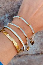 Close-up of a wrist wearing multiple bracelets with a neutral background