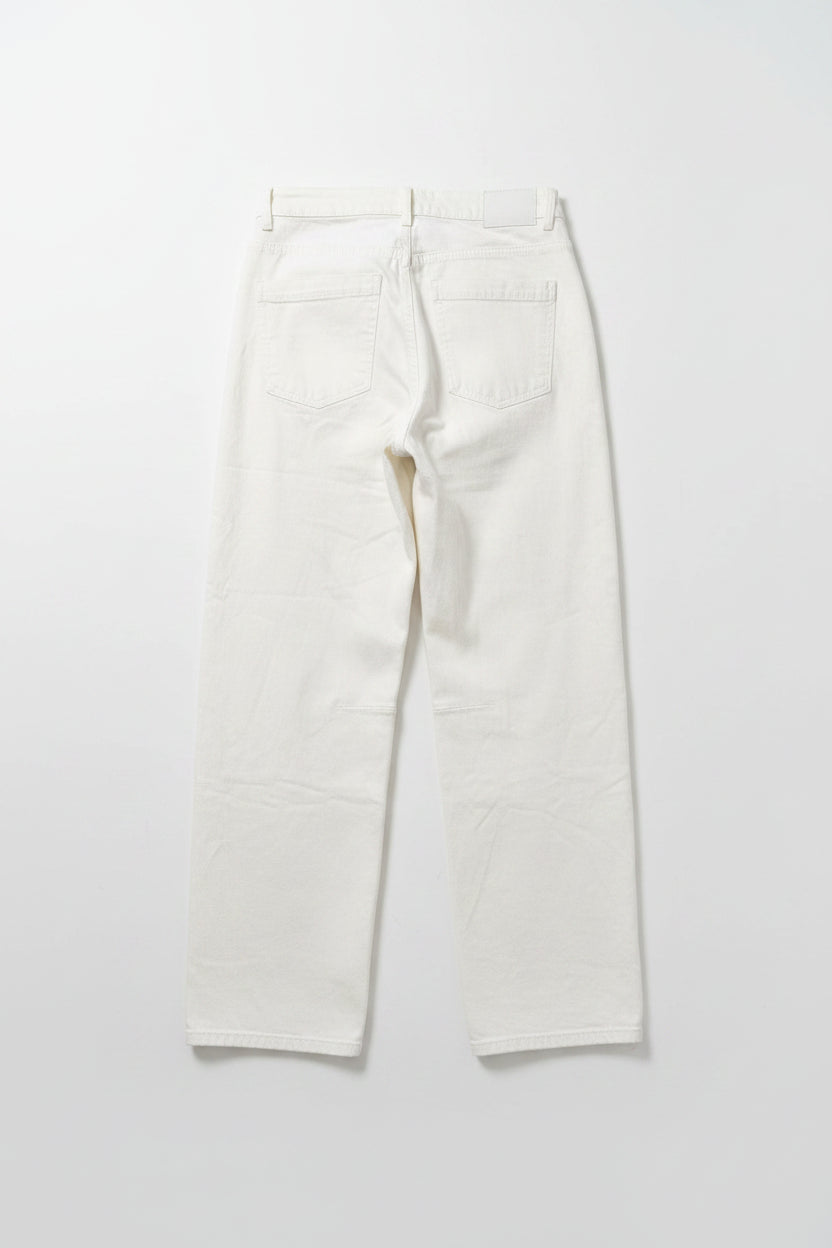 A pair of off-white cropped jeans with a relaxed straight-leg fit, hanging on a black hanger against a pink and red vertically striped background.