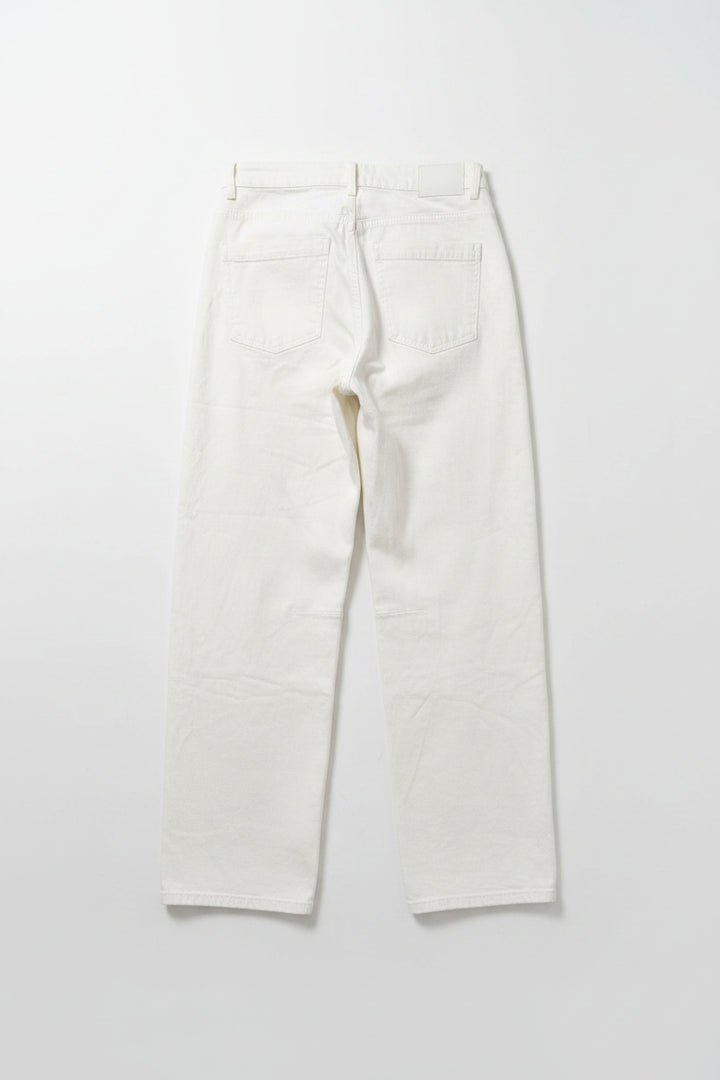 A pair of off-white cropped jeans with a relaxed straight-leg fit, hanging on a black hanger against a pink and red vertically striped background.