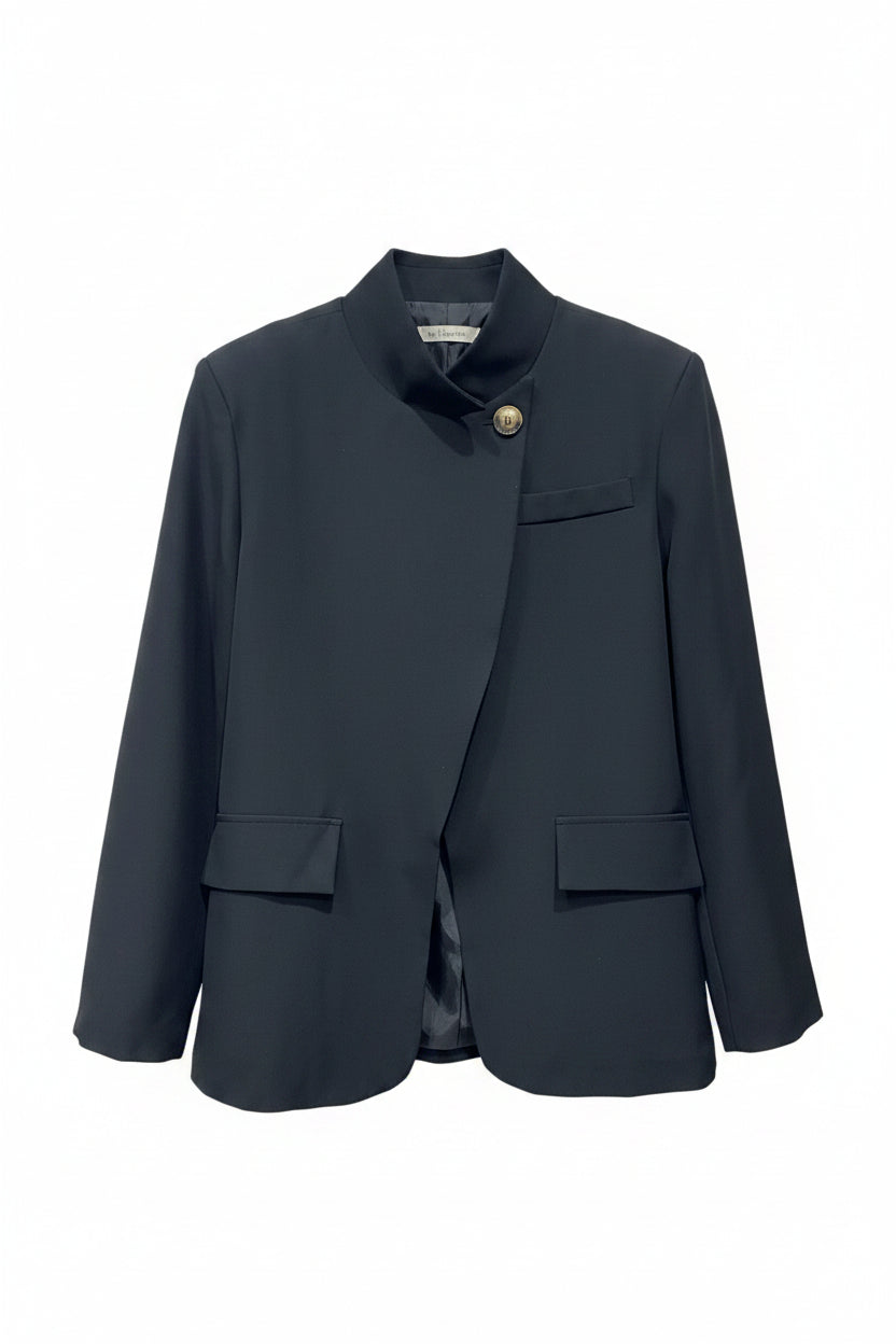 Dark gray blazer on a hanger against a light brick wall.