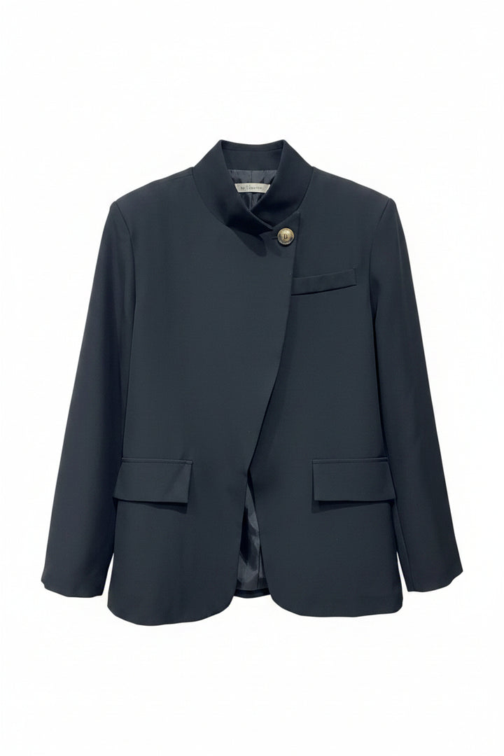 Dark gray blazer on a hanger against a light brick wall.