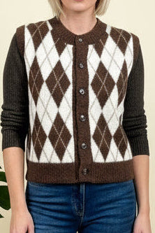 Person wearing a brown and white argyle patterned vest over a long-sleeve shirt.