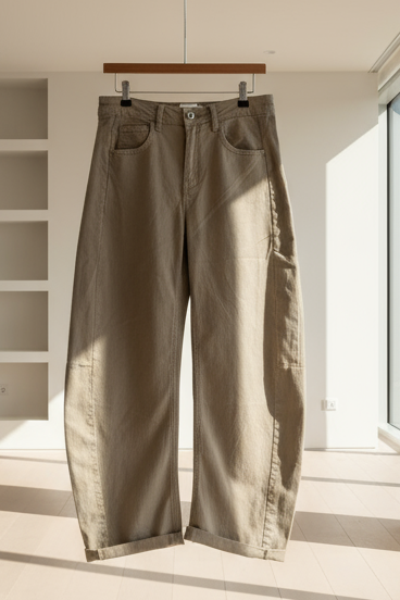 Beige pants hanging on a hook in a bright room with large windows.