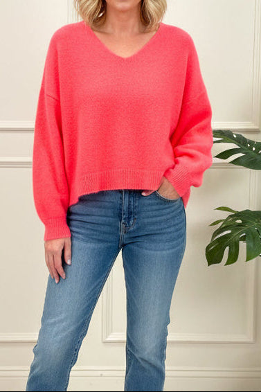 Person wearing a red sweater and blue jeans taking a mirror selfie.