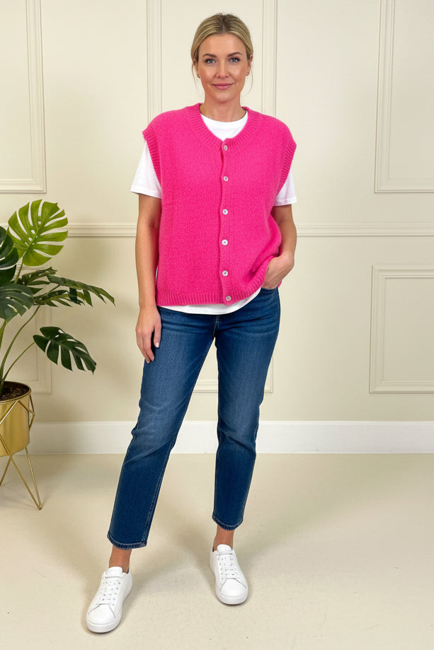 Person taking a mirror selfie wearing a pink shirt and blue jeans in a room with decorative elements.