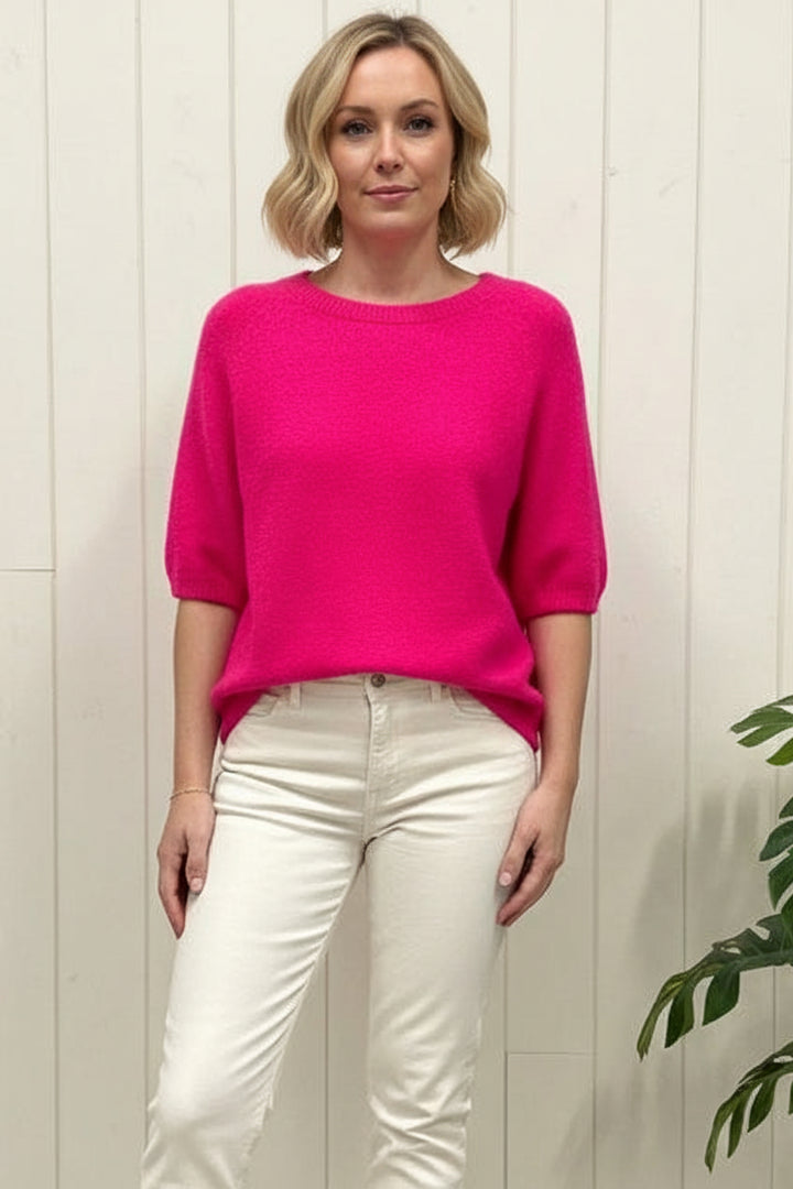 Person taking a mirror selfie wearing a pink shirt and blue jeans in a store.