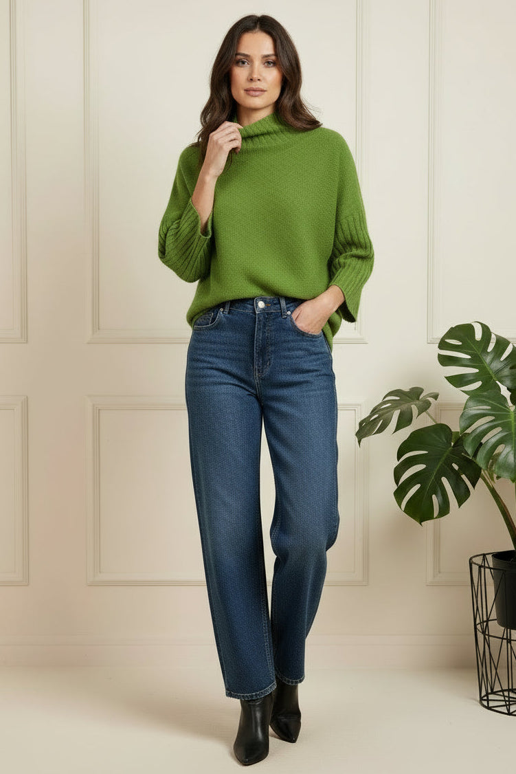 Green sweater on a white surface with a blurred background