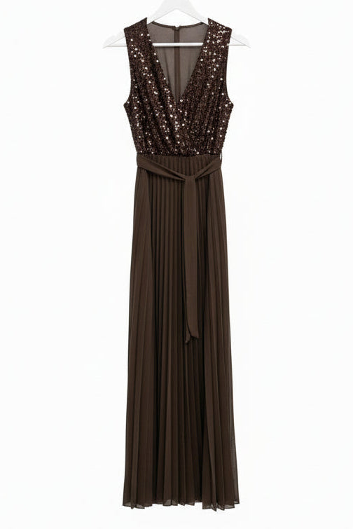 Black evening gown with sequin details on a hanger against a patterned wall.
