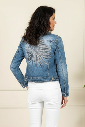 Woman wearing a denim jacket with a decorative back design on a plain background