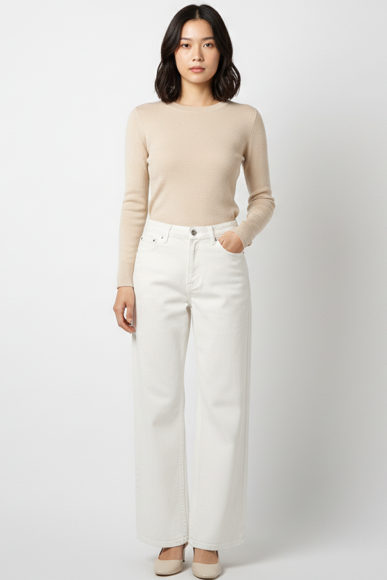 Woman wearing a beige sweater and white pants on a white background
