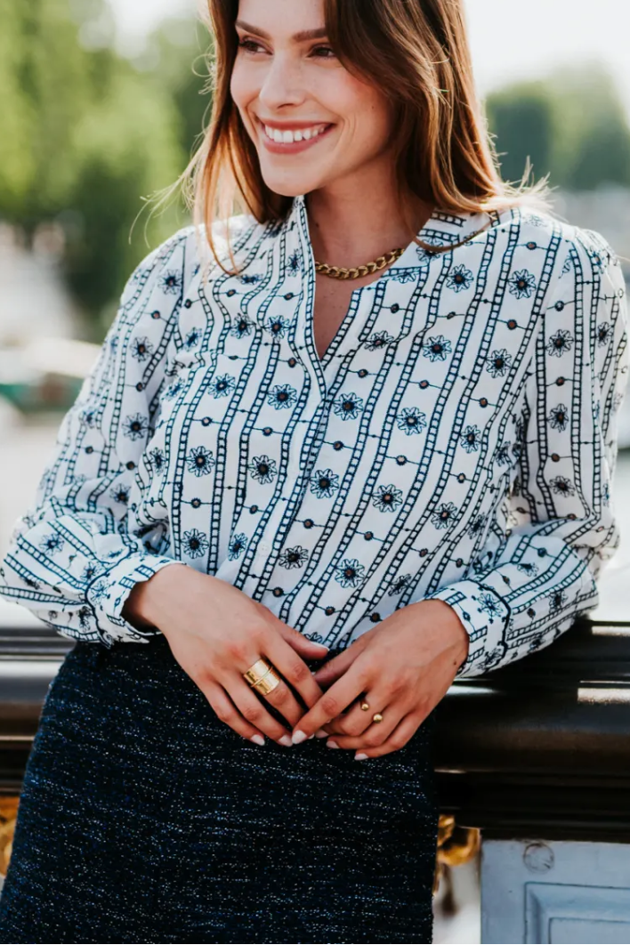 Woman wearing a patterned blouse and black skirt outdoors