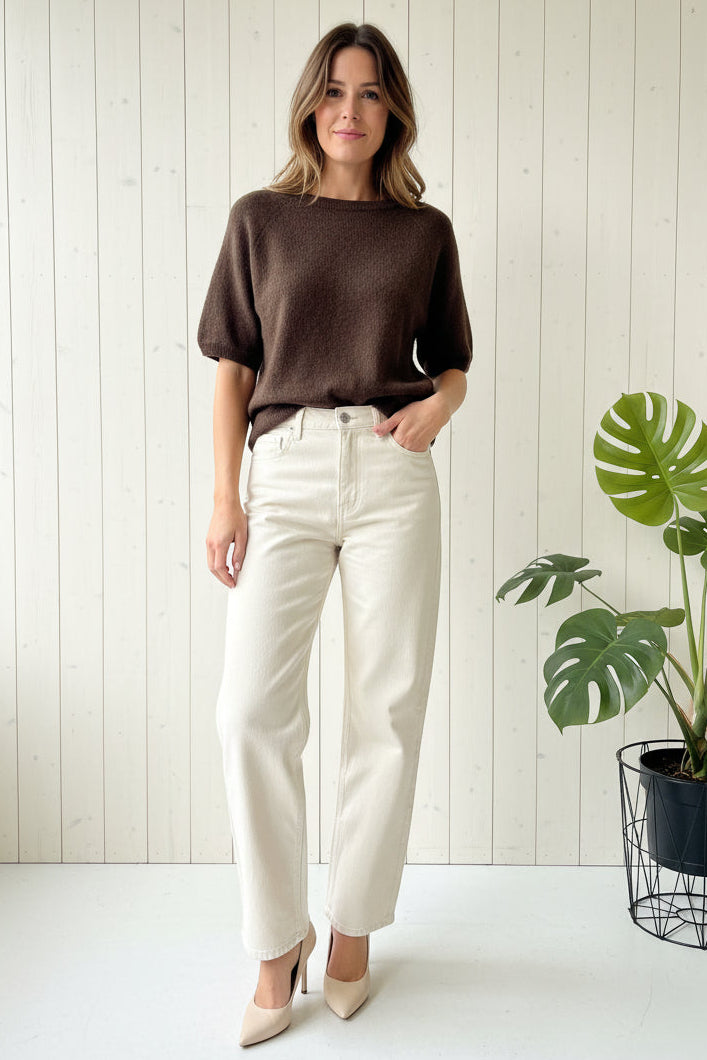 Brown sweater on a white hanger against a white wooden panel background