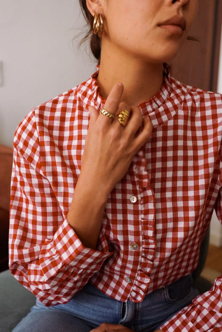 Person wearing a red and white checkered shirt with a blurred background
