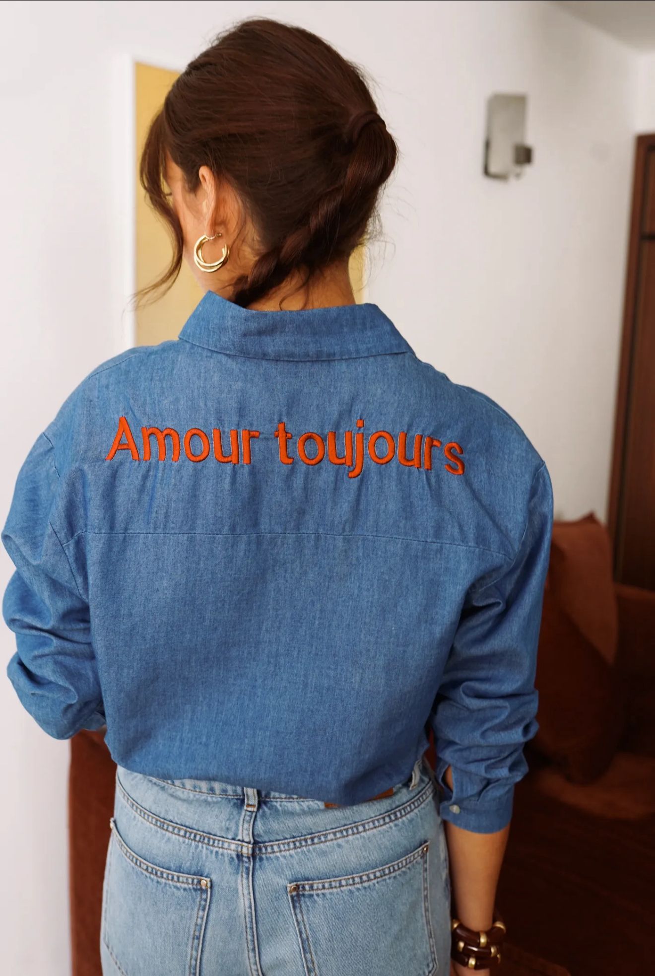 Person wearing a blue denim jacket with 'Amour toujours' text on the back.