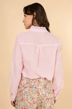 Woman wearing a light pink shirt and floral pants on a beige background