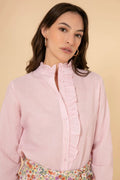 Woman wearing a pink blouse with ruffled details on a beige background