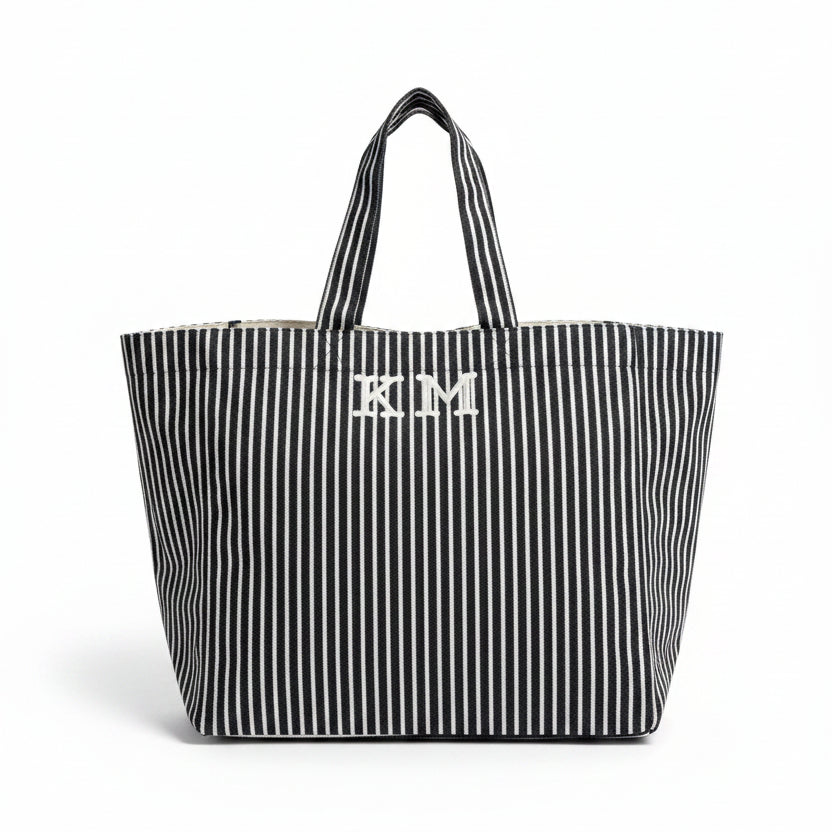 Black and white striped tote bag with 'KM' initials on a table in an indoor setting.