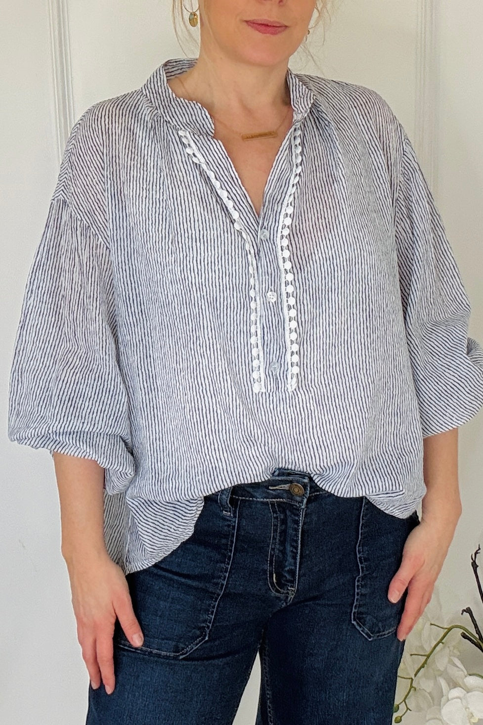 Person wearing a blue and white striped shirt with rolled-up sleeves and dark jeans.