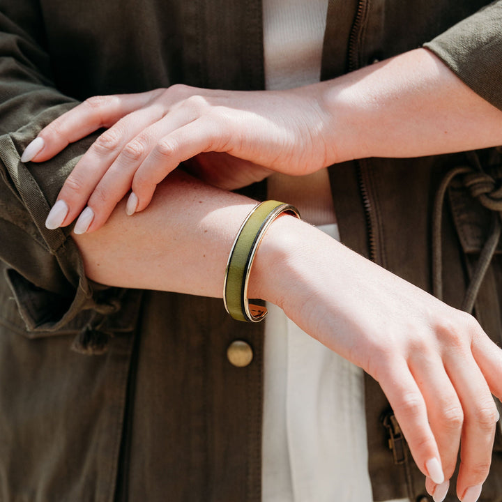 Person wearing a green leather bracelet on a blurred background