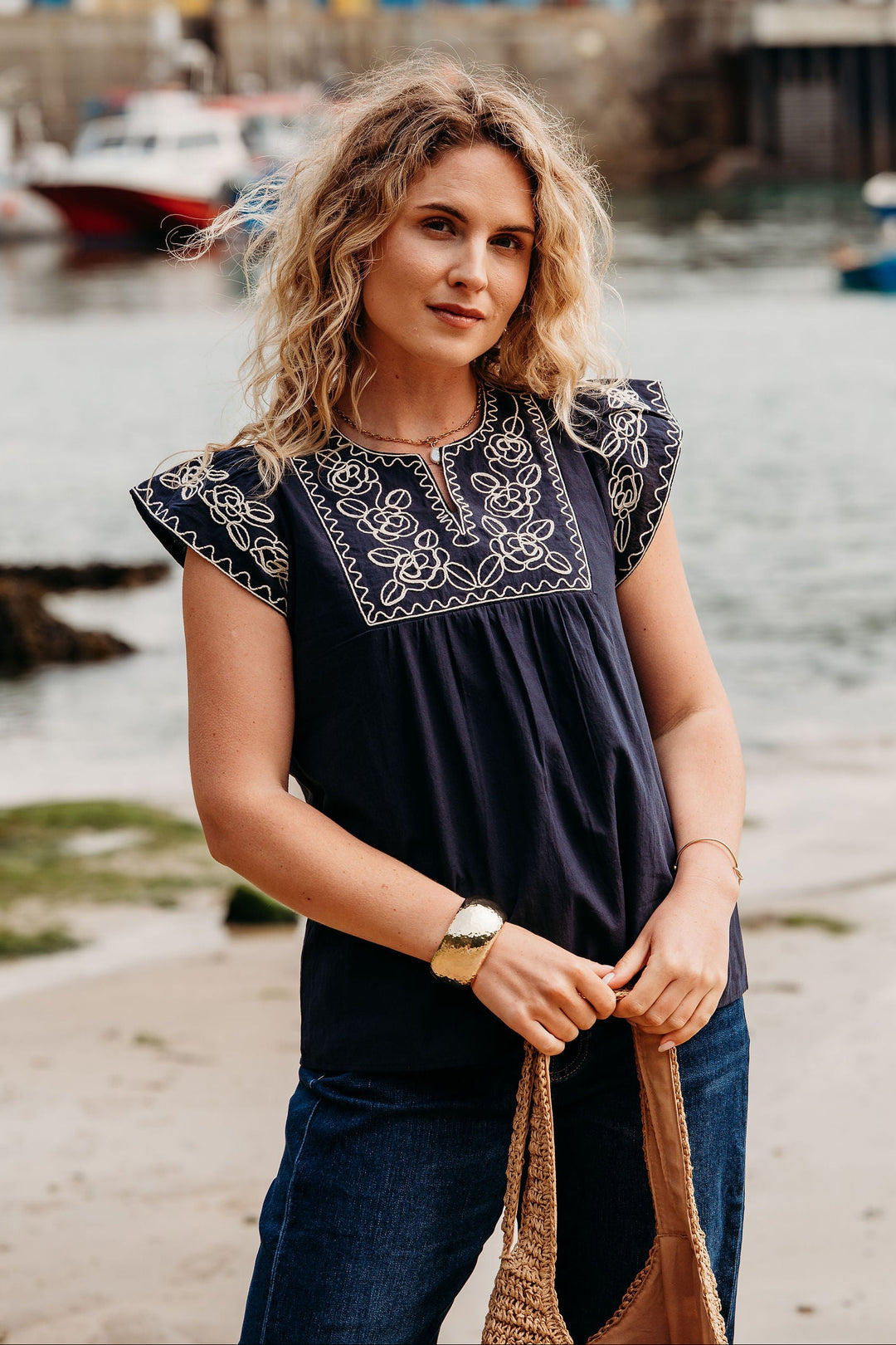 Woman standing by a waterfront with boats in the background