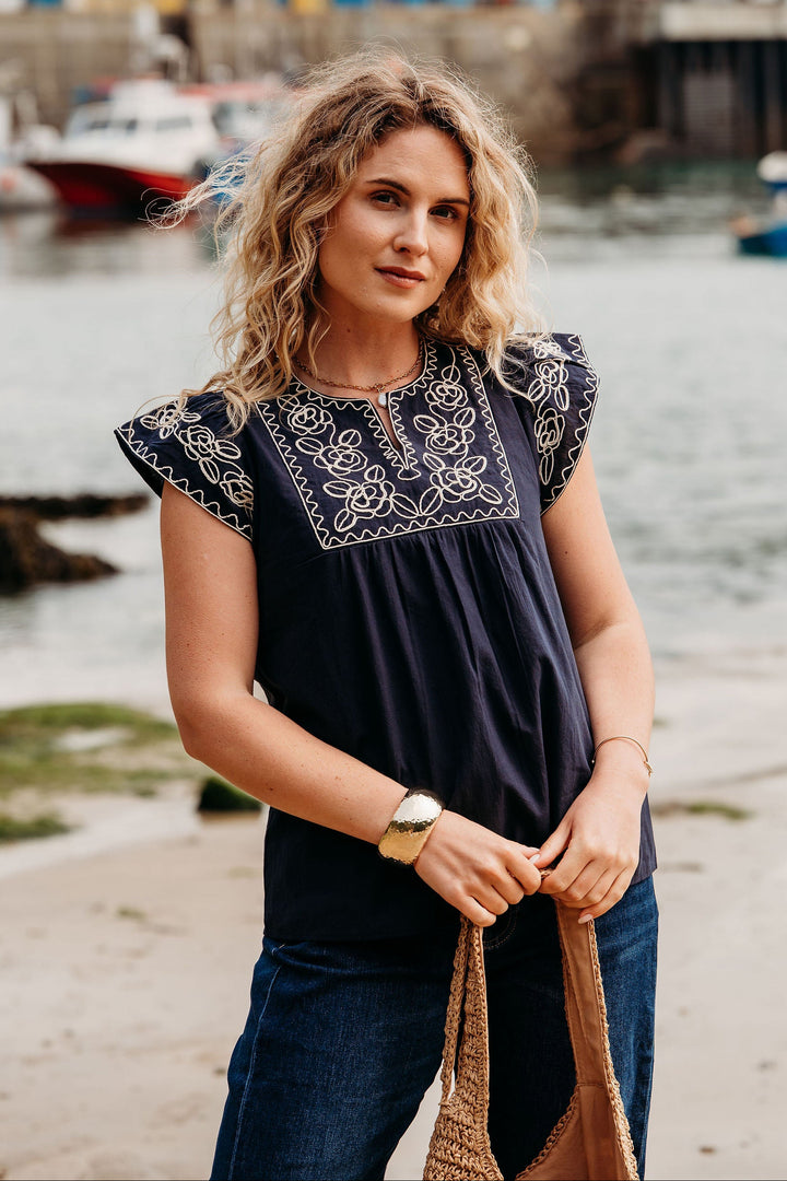 Woman standing by a waterfront with boats in the background
